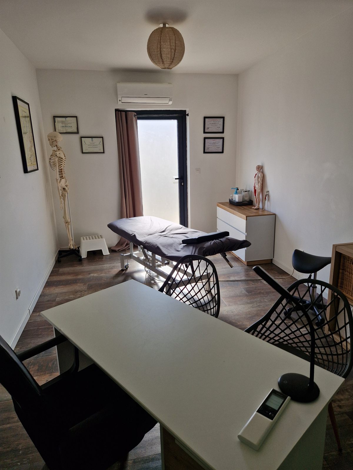 Salle de consultation du cabinet : table d'ostéopathie, bureau et squelette anatomique